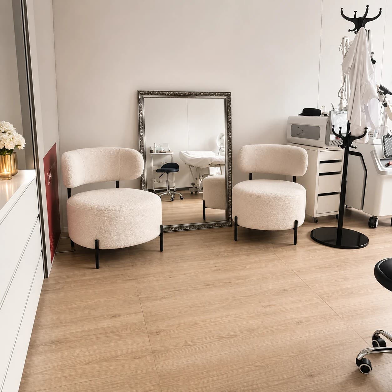 L'espace d'accueil du cabinet : fauteuils en bouclette crème, grand miroir et salle de soin en arrière-plan